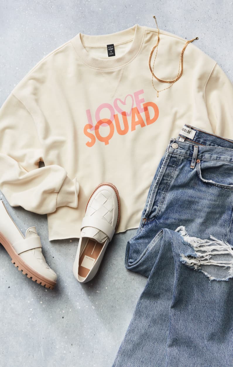 Lay down image of white sweatshirt, denim, and loafers